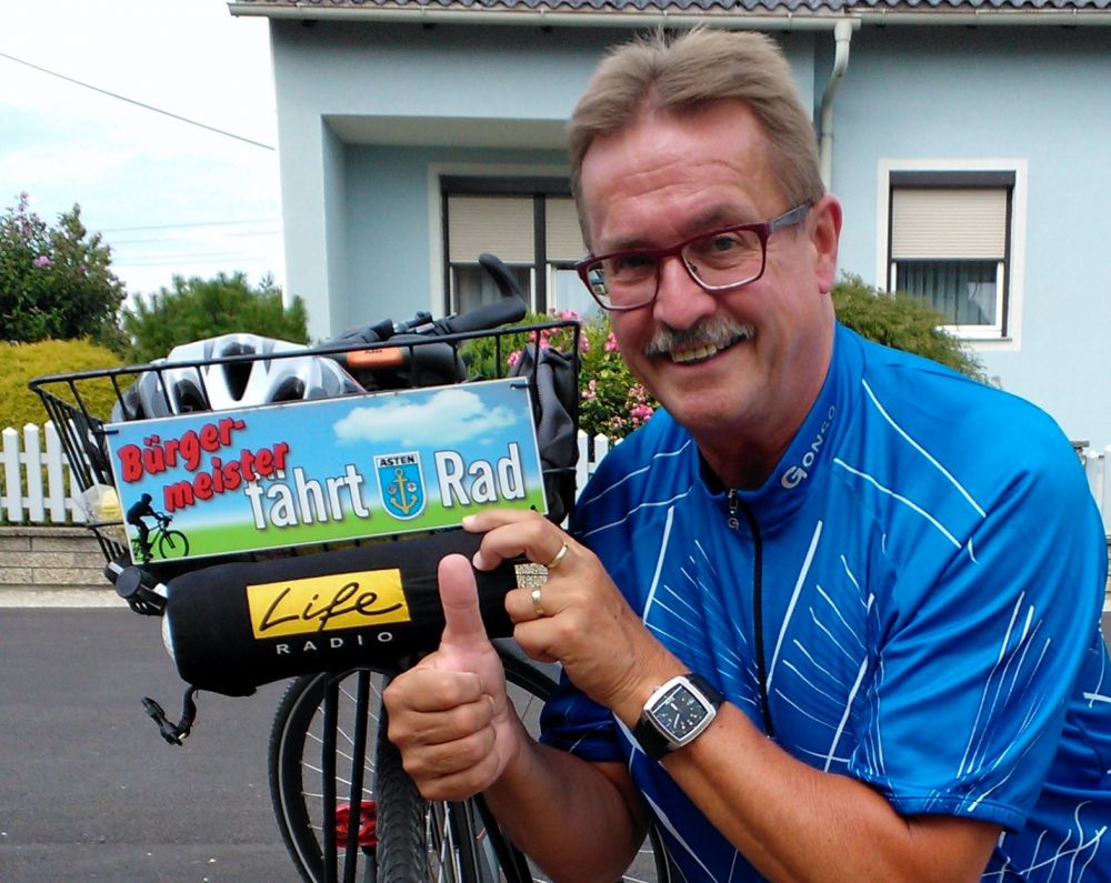 Mann mit "Bürgermeister fährt Rad"- Schild auf seinem Fahrrad