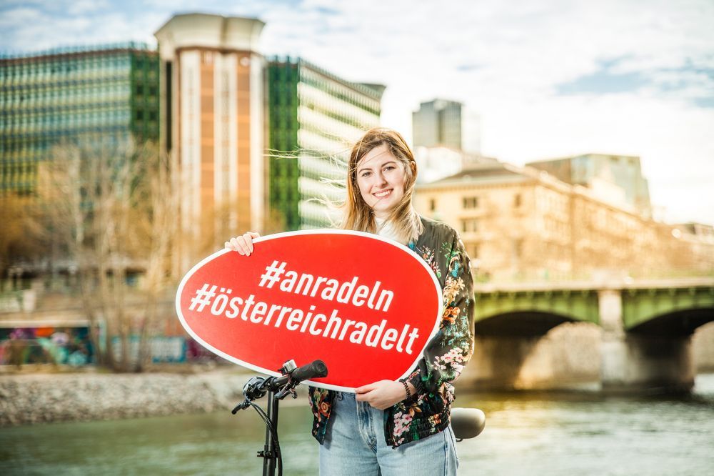 Frau mit Schild: 
#anradeln
#österreichradelt