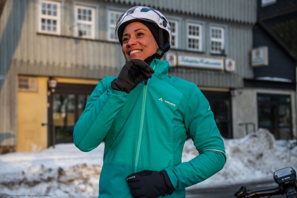 Frau in urbaner Winterlandschaft zieht sich die Jacke zu