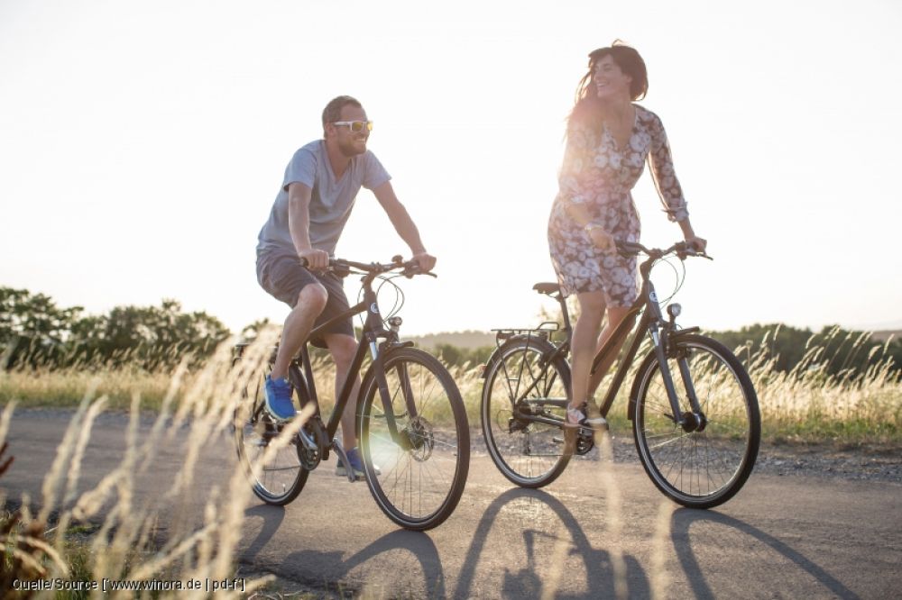Mann und Frau auf dem Fahrrad zwischen Feldern